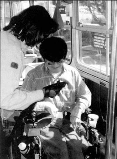 © photo of a wheelchair user being secured on a public bus