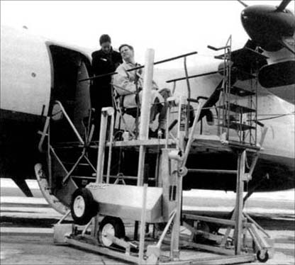 © Photo showing the use of a portable lift to assist a passenger using a wheelchair to board an airplane